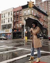 une femme qui traverse une rue avec son parapluie dans les mains